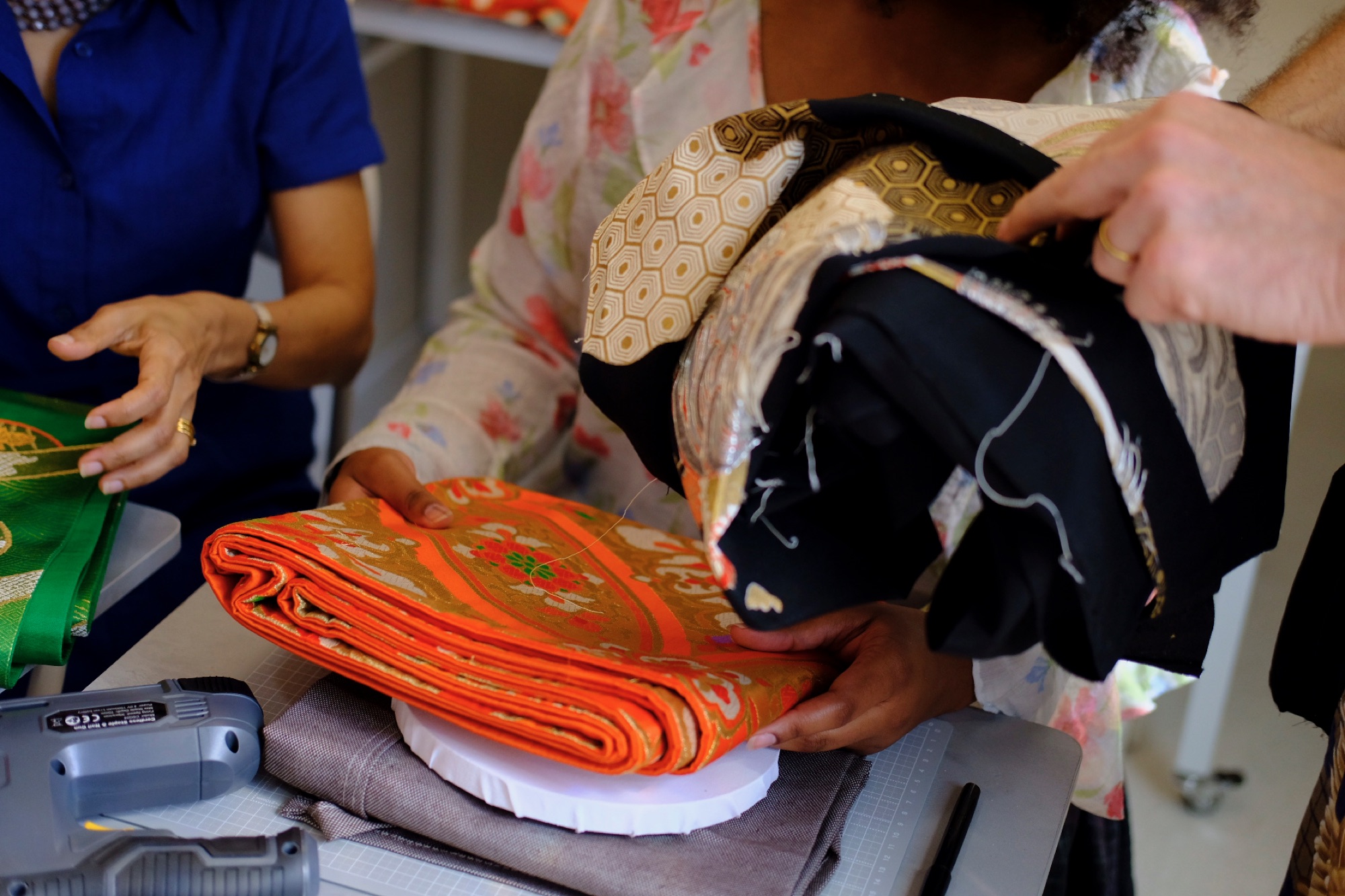 Guests examining bright orange, green, gold, and black obi