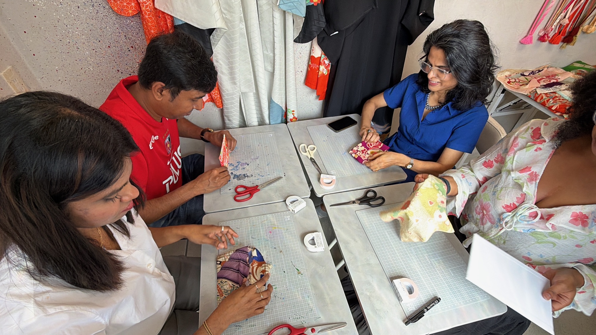 Four guests making individual kimono craft projects around the worktables